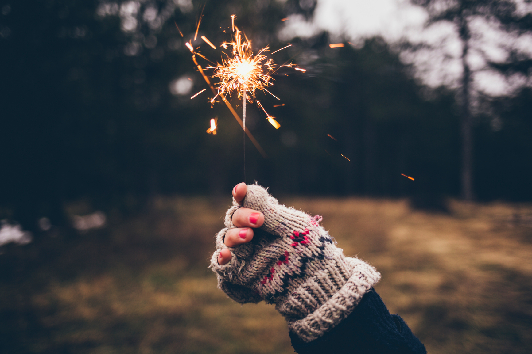 Woman holding a sparkler on a cold winter day.