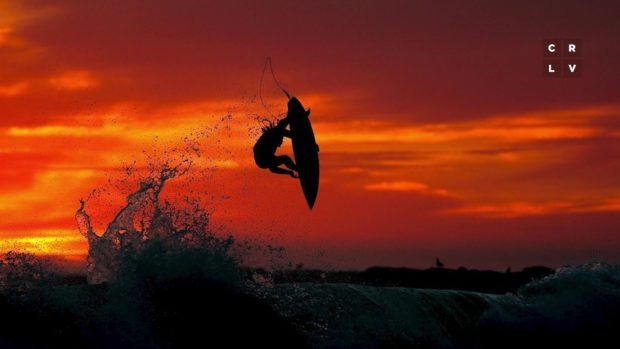 Surfer catches air off a wave in a red sunset sky, photo by Chris Burkard