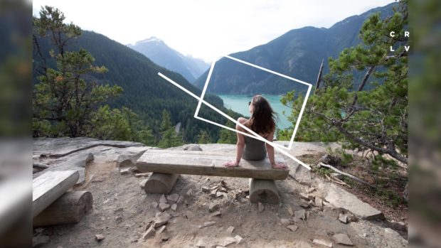 Girl sits on bench overlooking a lake in the mountains