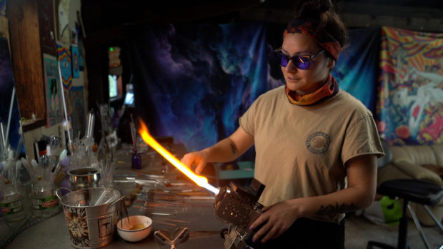 Glass artist Erin Bourguinon heats up glass on a flame in her studio while talking about stress