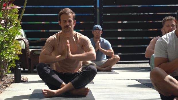 Matthew Callans sits on the ground cross legged in a prayer pose during yoga class to actively combat stress
