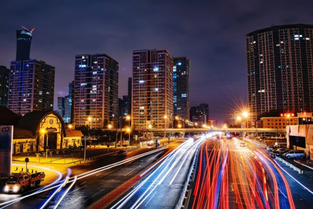 City skyline at night with long-exposure light trails from traffic